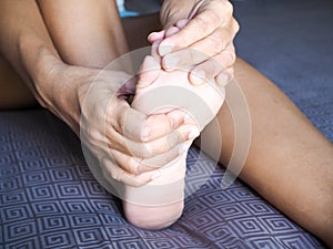 Young asian woman massaging on feet to relax muscle of foot pain, soles, heels and toe from foot injury or pain from disease