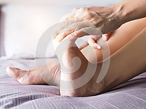 Young asian woman massaging on feet to relax muscle of foot pain, soles, heels and toe from foot injury or pain from disease