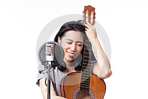 Young asian woman with microphone recording song and playing guitar in music studio, Woman performing in a recording studio for