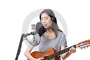 Young asian woman with microphone recording song and playing guitar in music studio, Woman performing in a recording studio for