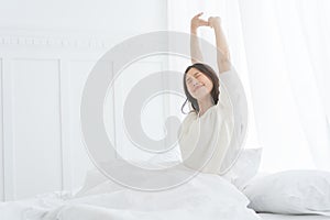 Young Asian woman in the morning she stretching in her bed in the bedroom.