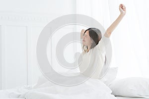 Young Asian woman in the morning she stretching in her bed in the bedroom.