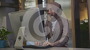 Young asian woman is muslim wearing headset working call center at office.