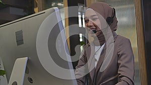 Young asian woman is muslim wearing headset working call center at office, assistant is islam using computer online.