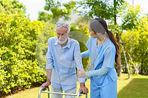 Young Asian woman nurse care giver helping senior old man with mobility walker in garden at home. Senior daycare center, Nurse