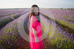Young Asian woman outdoors at lavender flowers field - happy and beautiful Chinese girl in sweet Summer magenta dress enjoying