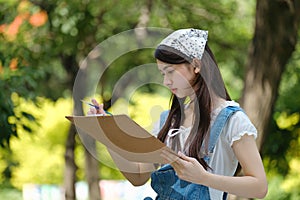 Young asian woman pianting and relaxing in park