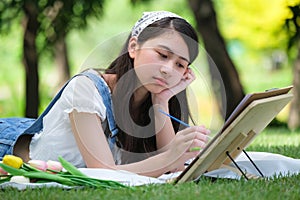 Young asian woman pianting and relaxing in park