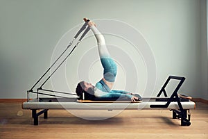 Young asian woman pilates stretching sport in reformer bed instructor girl in a studio photo