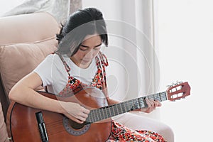 Young Asian woman play guitar. Home hobbies and recreations