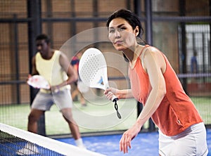Young asian woman playing padel on a hard court