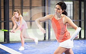 Young asian woman playing padel on a hard court