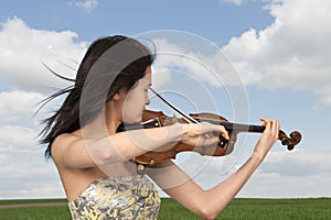 Young asian woman playing the violin outdoors