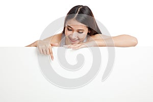 Young Asian woman point down behind a blank sign