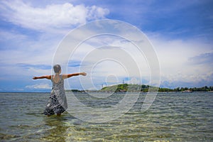 young Asian woman posing with opened arms on beach in Bali Indon