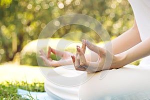 Young Asian woman practicing meditation in park. Closeup hands w