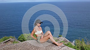 Young Asian woman practicing yoga on the cliff of mountain with a sea view