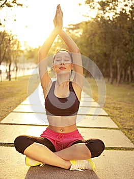 Young asian woman practicing yoga outdoors at sunset