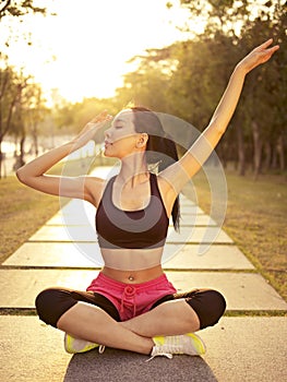 Young asian woman practicing yoga outdoors at sunset