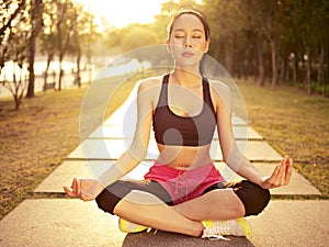 Young asian woman practicing yoga outdoors at sunset