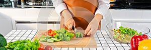 Young Asian woman is preparing healthy food vegetable salad by Cutting ingredients on cutting board on light kitchen, Cooking At