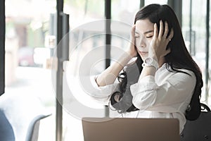 young asian woman put hand on head feeling tired at office. businesswoman frustrate and stress from hard work while sitting
