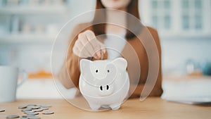 Young Asian woman putting coin in piggy bank