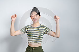 Young asian woman raising arms while smiling and screaming to celebrate after successfully work