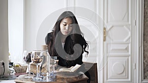 Young Asian woman reading a book and drinking water