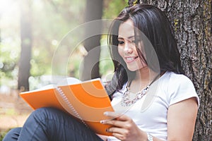 Young asian woman reading a book outdoor in a park