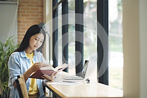 Young asian woman sitting and reading book.