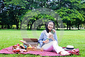 Young Asian woman relax time in park.In the morning she is sipping tea ,
