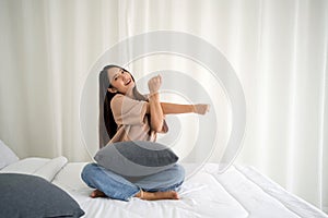 Young asian woman are relaxed and stretching her arms on bed at home. Morning fitness, mindfulness concept