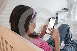 Young asian woman relaxing and using smartphone on white bed