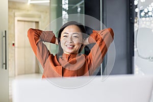 Young Asian woman resting in the office, successfully completed the work, satisfied with the results of the achievement