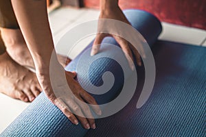 Young asian woman rolling blue yoga mat or fitness mat in livingroom, Healthy concept, Mind-body improvements concept