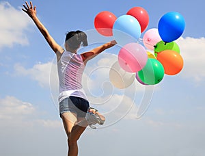 Young asian woman running with colored balloons