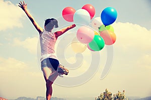 Young asian woman running with colored balloons