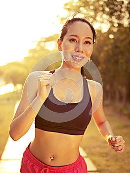 Young asian woman running in park