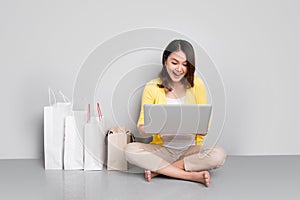 Young asian woman shopping online at home sitting besides row of shopping bags