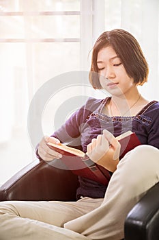 Young asian woman short hair read a book in living room