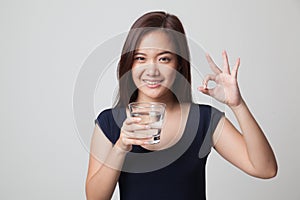 Young Asian woman show OK with a glass of drinking water.