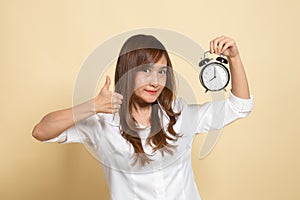 Young Asian woman show thumbs up with a clock