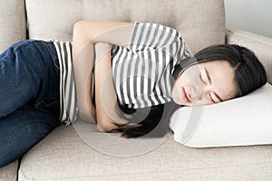 Young asian woman sit on sofa in the living room, women having painful stomachache