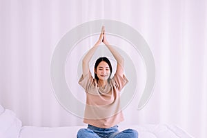 Young asian woman sitting on bed practicing doing yoga meditation,Workout exercise after waking up in morning,Healthy and lifestyl photo