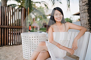 Young Asian woman sitting on bench relax on beach, Beautiful female happy relax near sea. Lifestyle women travel on beach concept