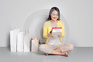 Young asian woman sitting besides row of shopping bags holding r