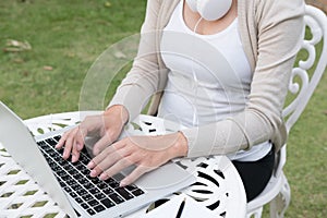 Young asian woman sitting on chair with headphone using laptop.