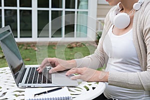 Young asian woman sitting on chair with headphone using laptop.