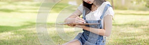 Young asian woman sitting drawing picture with colorful paint brush while leisure in the park on summer.